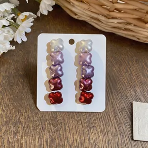 Close-up of gradient five-tier cross-shaped earrings in red and purple tones.