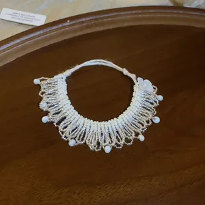 Elegant handmade white beaded necklace with silver fringe details and a delicate flower charm.