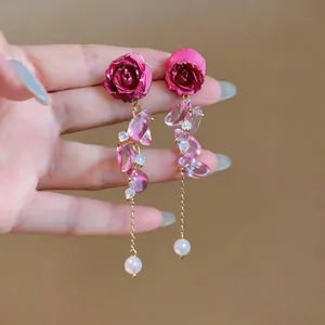 Detail view of elegant red rose earrings featuring pink crystals and pearl drops