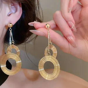 Detail of gold multi-layered circular textured earrings with high-shine metallic finish