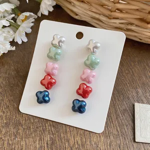 Detailed close-up showing five pairs of colorful flower-shaped stud earrings on card