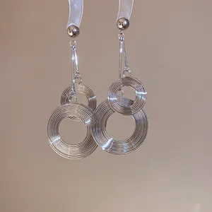 Close-up of silver-colored layered circular metallic drop earrings with textured finish