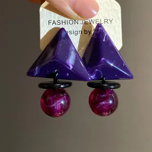 Detailansicht von geometrischen Harz-Ohrringen mit violettem Dreieck und magentafarbener Kugel.