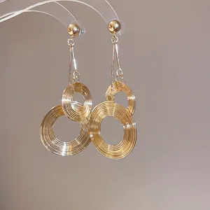 Detailed close-up showing the intricate textured surface of gold metal round dangle earrings.