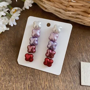 Detailed view of elegant gradient purple and red clover-shaped stud earrings on card