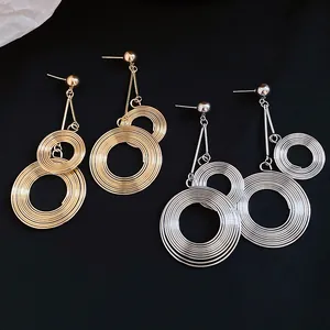 Macro detail of fashionable gold and silver layered circular textured metal drop earrings