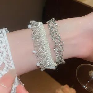 Detailed view of layered pearl fringe and sparkling silver bracelets on wrist.