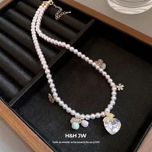 Elegant pearl necklace with heart zircon pendant and butterfly charms on jewelry tray
