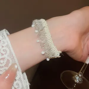 Close-up of elegant handmade pearl tassel beaded bracelet worn on a wrist with lace detail