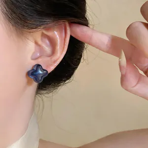 Close-up detail showing an elegant blue clover flower stud earring worn on a model's ear