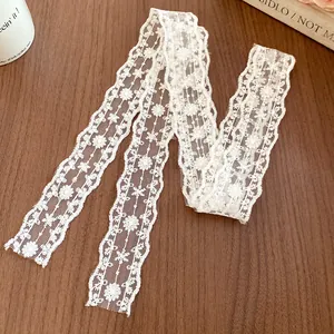 Detailed close-up of a white floral lace streamer necklace on a wooden background