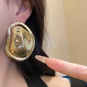 Close-up of gold oval hammered metal earring worn on ear with wrinkled texture