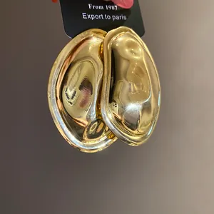 Detailed view of chunky golden oval earrings with unique wrinkled metallic texture