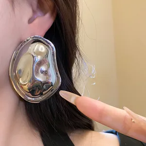 Macro detail view showing the metallic chrome texture of large oval wrinkled earrings