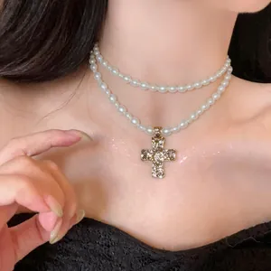 Detailed close-up of a layered white pearl necklace with a vintage gold cross pendant.