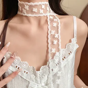 Close-up of white lace neck ribbon with delicate floral embroidery details