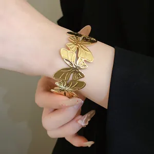 Elegant macro detail showing a gold pleated butterfly open cuff bracelet on a wrist