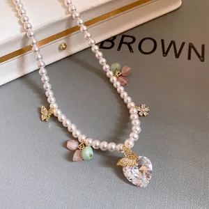 Detail of pearl necklace with heart-shaped zircon and golden butterfly charms