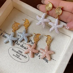 Elegantes pendientes de estrella de mar bañados en oro 18k con diseño de caracola