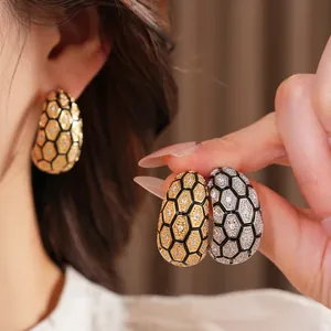 Gros plan de boucles d'oreilles en C avec un motif alvéolé en zircon brillant.