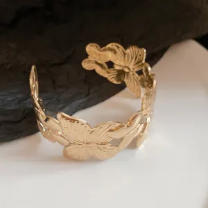 Detailed view of a gold-toned butterfly motif open cuff bracelet with textured wings