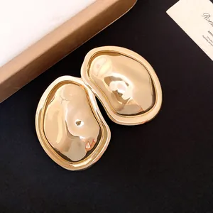 Close-up of minimalist gold metallic oval wrinkled earrings with luxury texture