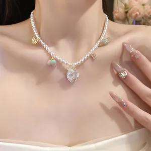 Detailed view of a pearl necklace with a large heart zircon pendant and butterfly charms.
