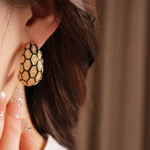 Gros plan détaillé de boucles d'oreilles en C plaquées or 18 carats avec motif nid d'abeille