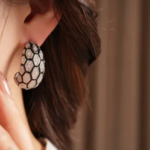 Gros plan de boucles d'oreilles en C avec motif hexagonal pavé de zircons.