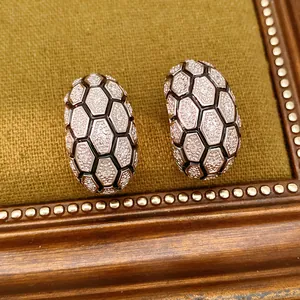 Gros plan de boucles d'oreilles en C avec motif nid d'abeille hexagonal et pavage