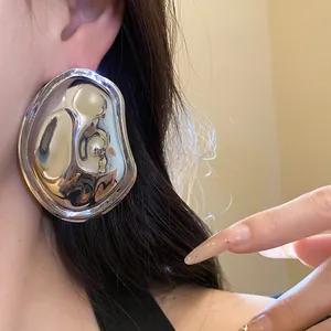 Close-up view of a metallic silver oval wrinkled earring showing high-shine liquid texture