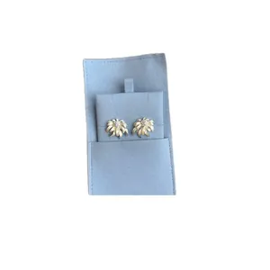 Elegant gold chamomile flower stud earrings with center stones on light blue pouch