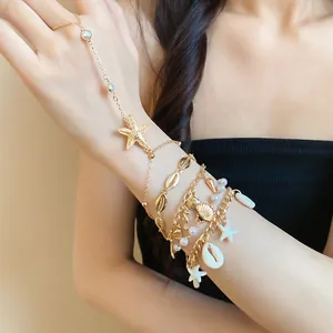 Bohemian gold-tone charm bracelet set featuring sea shells and starfish on a female model arm