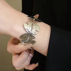 Close-up of metallic silver open cuff bracelet with pleated butterfly design on wrist