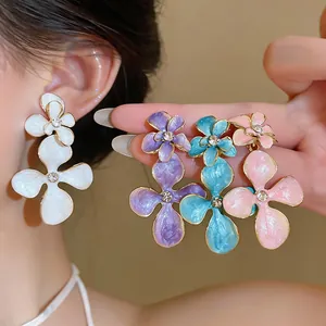 Close-up of colorful vintage floral earrings with drip oil finish and rhinestones