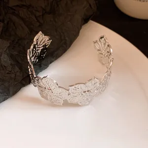 Detailed view of silver-tone metal cuff bracelet with intricate floral petal cutout design.