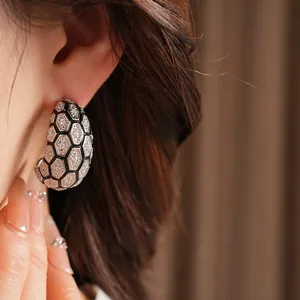 Gros plan de boucles d'oreilles en forme de C, plaquées or 18 carats avec oxydes de zirconium.
