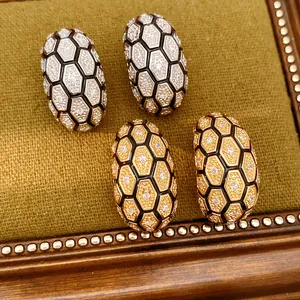 Gros plan de boucles d'oreilles en C à motif nid d'abeille avec zircons en or et argent