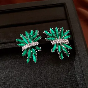 Dettaglio ravvicinato di eleganti orecchini a perno con strass verdi a forma di fuoco