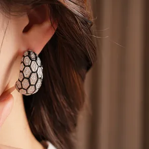 Gros plan de boucles d'oreilles C en plaqué or 18k avec motif nid d'abeille et zircon.