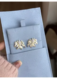 Close-up detail view of elegant chamomile flower ear studs on a light blue display card