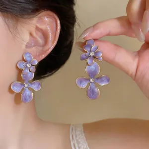 Macro detail of vintage purple enamel flower drop earrings with sparkling rhinestone center