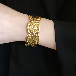 Detailed view of a fashionable gold pleated butterfly metal open cuff bracelet on a female wrist