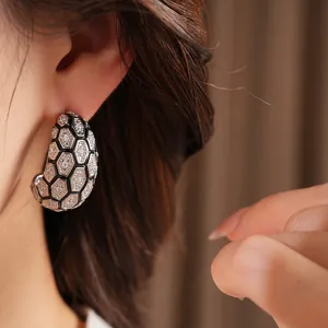Gros plan de boucles d'oreilles en C avec zircons et motif en nid d'abeille