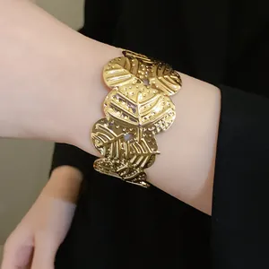 Close-up shot of a textured gold metal cuff bracelet with butterfly wing design patterns