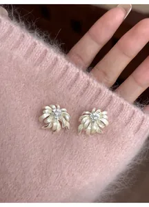 Macro view of chamomile flower stud earrings with crystals on pink knit fabric