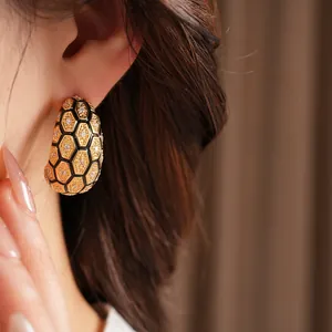 Détail de boucle d'oreille en C plaquée or 18 carats avec zircons et motif nid d'abeille
