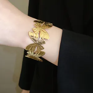Close-up detail of a luxury gold-toned metallic butterfly cuff bracelet worn on a wrist