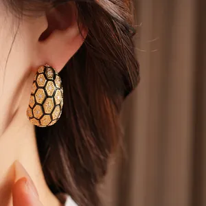Gros plan de boucles d'oreilles en C plaquées or 18 carats avec motif nid d'abeille
