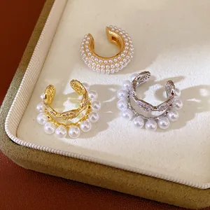 Detalle de elegantes pendientes de clip de doble capa con perlas y circonitas brillantes
